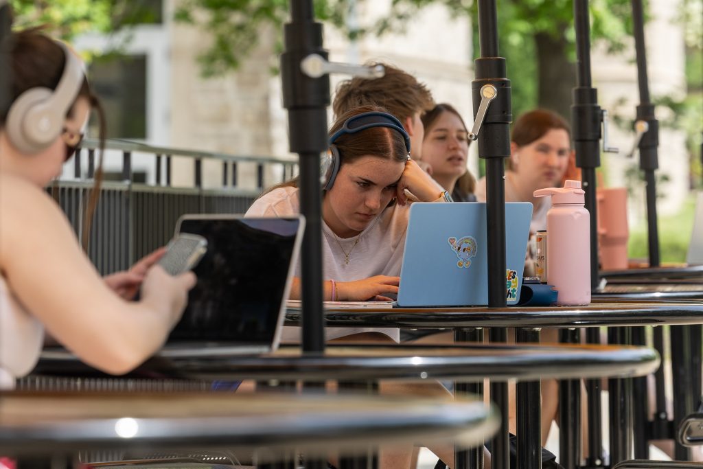 A college student works on a computer outside.