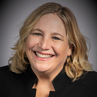 A woman with short blonde hair smiling.