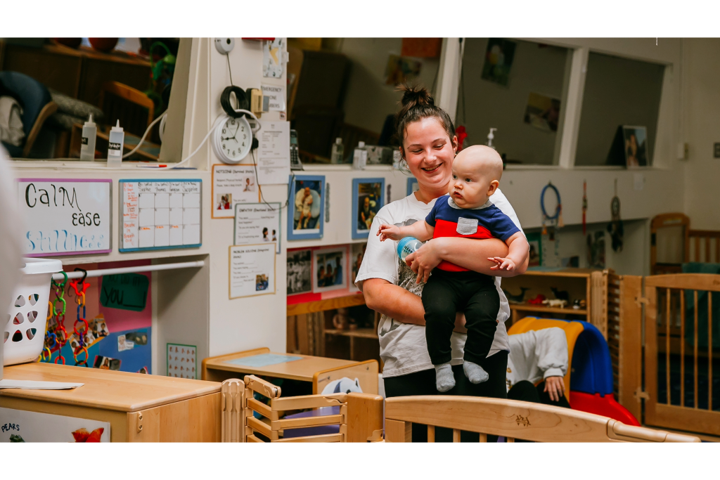 An woman holding a baby in an early childhood education and care center.