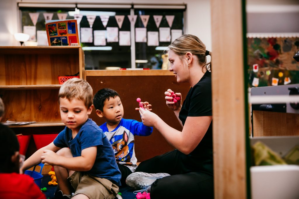 A woman plays with a young boy at an early childhood education program.