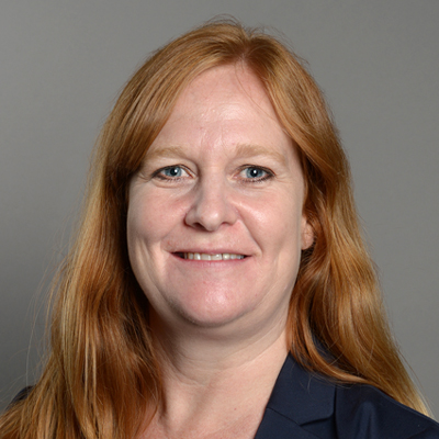 A woman with long red hair smiling.